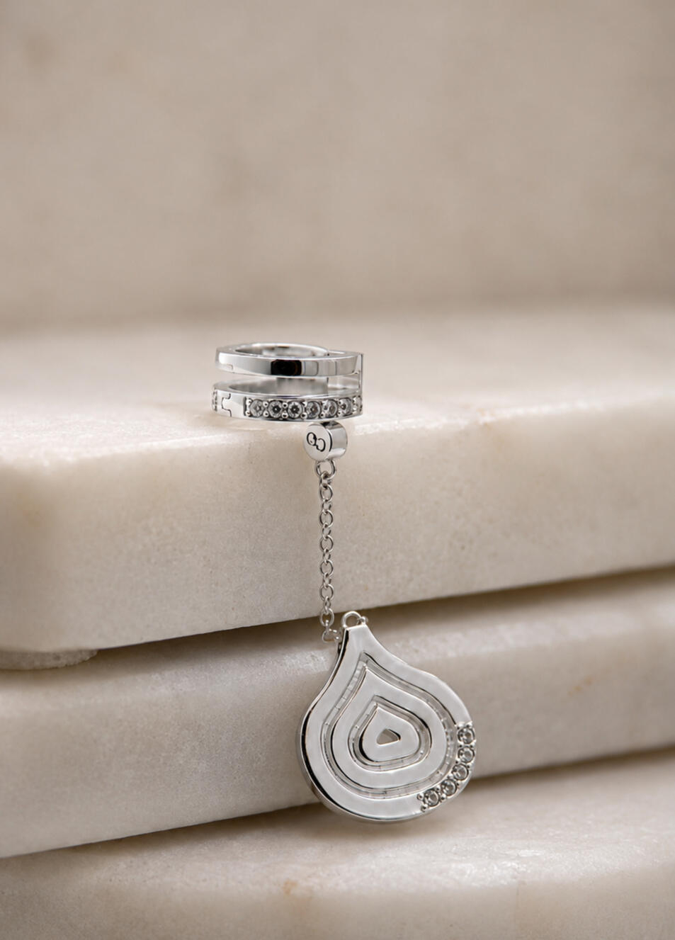 a silver hair cuff and pendant, screwed in together on tiles